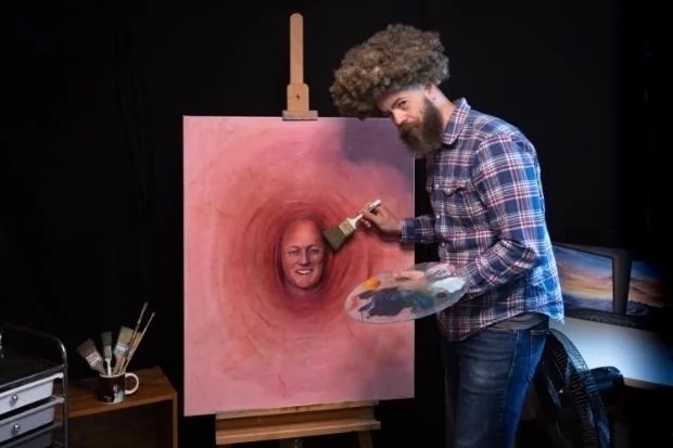 A man dressed like Bob Ross is humorously painting a pink canvas featuring a Prime Minister’s face.